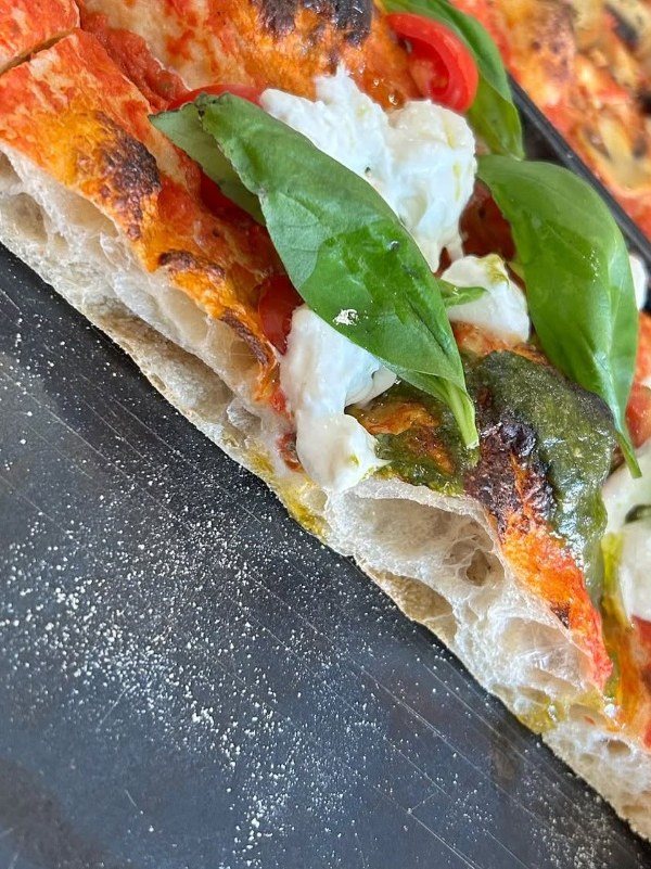 Trancio BIGA Pizza al Taglio con pomodoro, stracciatella, basilico e pesto, impasto alveolato su teglia scura